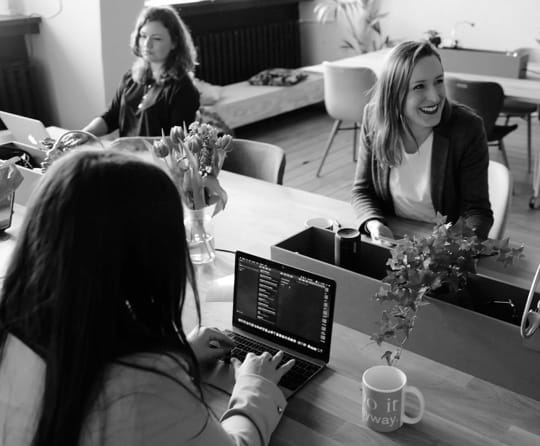 Three people sitting at computers around a desk