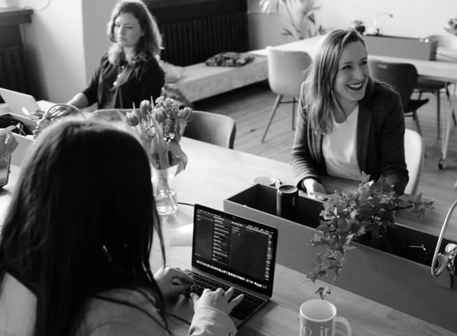 Three people sitting at computers around a desk